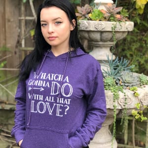 A young woman wearing a hoodie with words printed on the front. It reads, "Whatcha gonna do with all that love?"